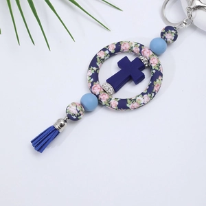 Detail of blue silicone cross keychain with floral bead and elegant tassel accessory