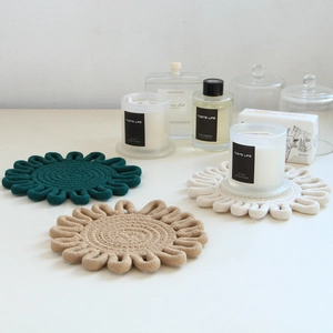 Detail view of woven cotton coasters in dark green, beige, and off-white flower shapes