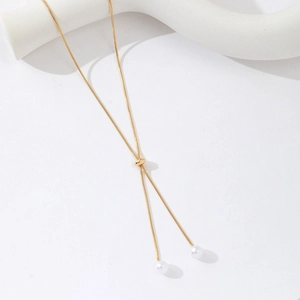 Detail of adjustable gold snake chain Y-necklace with elegant white pearls on white art stand