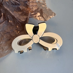 Detail of cream acetate bow claw clip with black trim and elegant french style