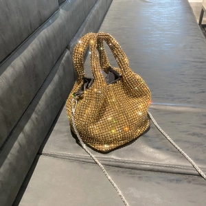 Macro detail of golden rhinestone bucket bag with shimmering crystals and silver chain