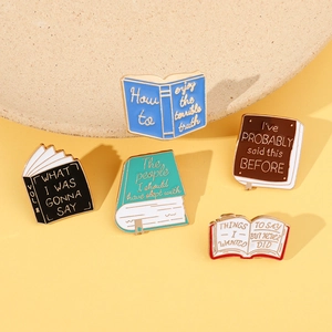 Close-up of five colorful enamel book pins with creative literature quotes on metal badges
