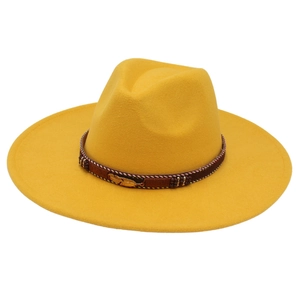 Close-up of a yellow wool felt fedora featuring a braided band and golden feather detail