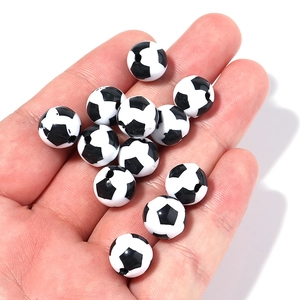 Close-up of hand holding 12mm football pattern acrylic beads for DIY jewelry making