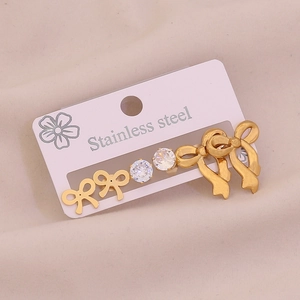 Three pairs of golden stainless steel stud earrings with bows and cubic zirconia on card