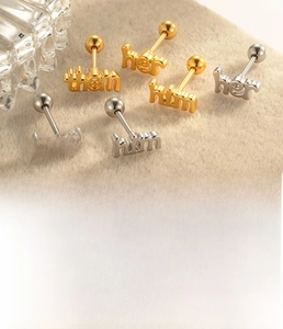 Detailed view of stainless steel cartilage studs with engraved them her him text
