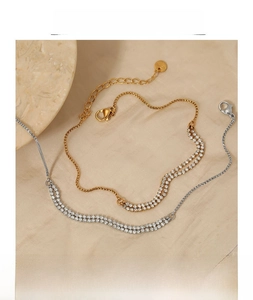 Detailed close-up of gold and silver anklets with zircon stones on soft fabric