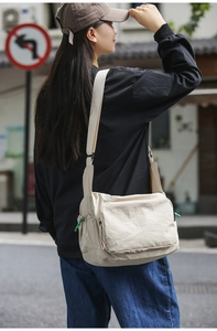 Detail view of the cream-white waterproof nylon messenger bag with front zipper pocket