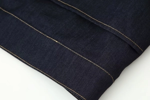 Vue macro du sergé de denim bleu foncé avec des coutures contrastées jaunes précises