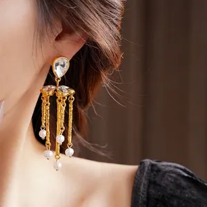 Vintage gold tassel earrings with teardrop rhinestones and pearls on a model