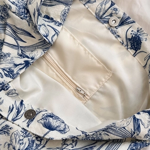 Detail of blue floral cotton tote bag showing zipper pocket and magnetic buckle