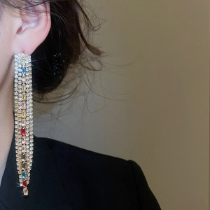 Detailed close-up of long tassel earrings with multicolored zircons and gold-plated finish