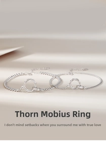 Detailed close-up of Mobius thorn interlocking rings on a silver Cuban chain bracelet