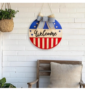 American flag themed wooden welcome sign with striped bow on a white brick wall