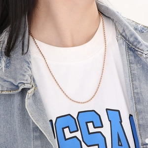 Close-up of minimalist rose gold twist rope chain necklace worn on a casual outfit