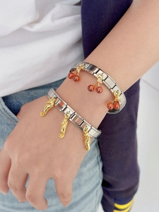 Detailed close-up of stainless steel bracelets with red cherry and gold seahorse charms