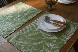 Detailed texture of forest green linen placemat with white botanical leaf patterns