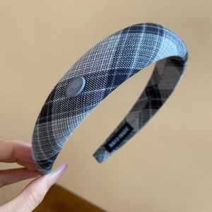 Detail of grey plaid thick headband showing Korea button and Handmade textile label