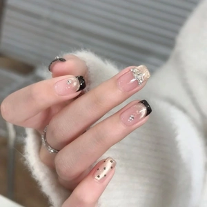 Short black French press-on nails with golden cat-eye glitter, rhinestones and polka dots