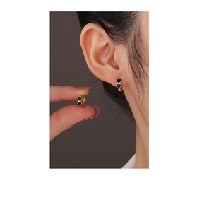 Close-up of gold double black heart earrings showing detailed size and wearing effect