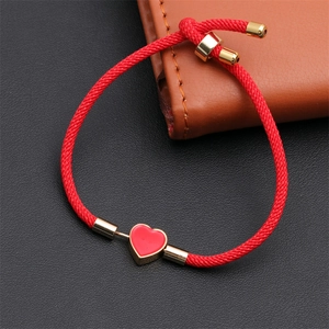 Detail of red braided Milanese rope bracelet featuring a golden enamel heart pendant