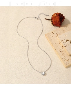 Dettaglio della collana a cuore in argento S925 con diamanti su sfondo materico