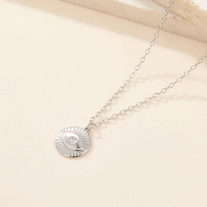 Macro view of a silver Evil Eye pendant with diamond inlay on a fine O-link chain