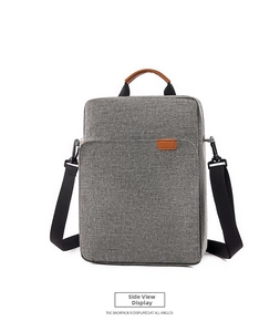 Detail of grey Oxford fabric briefcase with brown leather handles and nylon shoulder strap