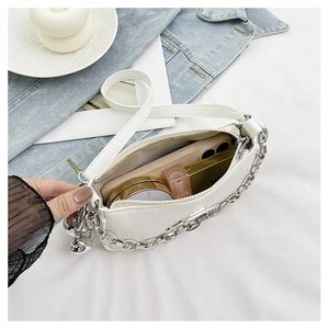 Interior view of white shoulder bag with silver chain showing storage for phone and lipstick