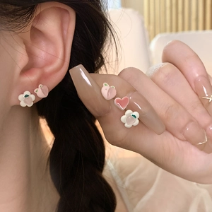 Detalle macro de conjunto de pendientes de melocotón y fresa usados por la modelo