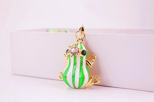 Macro detail of golden frog keychain with green enamel and sparkling crystal eyes