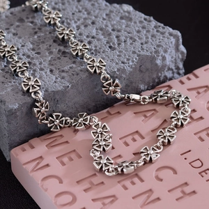 Vintage silver hip-hop necklace with cross flower links displayed on rustic stone blocks