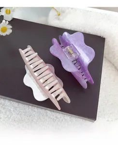 Detail of pink and purple cloud-shaped hair claws with glitter finish on a book