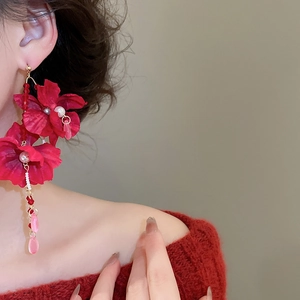 Detailed close-up of a long red fabric flower earring with crystal drop pendants