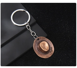 Detail shot of vintage bronze cowboy hat keychain with Sayko's engraving and metallic chain