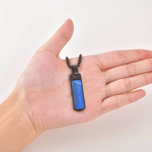 Close-up of rectangular lapis lazuli pendant held in palm with black metal bead chain