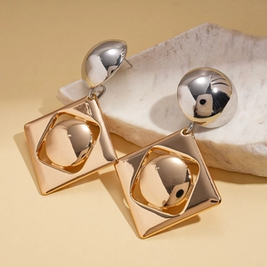 Detailed shot of mixed metal geometric earrings on a white stone background