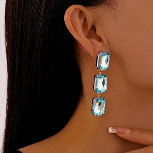 Detail of luxury geometric earrings with triple rectangular light blue crystals on model
