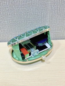 Open peacock evening clutch showing interior space for phone, makeup and perfume