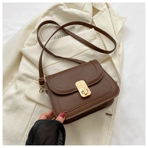 Detail of vintage brown leather crossbody bag with a rectangular gold metal turn lock