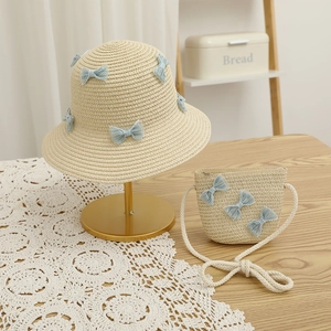 Detail of straw hat and matching bag set with cute blue mesh bows for summer sun protection