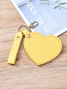 Detail of a yellow heart-shaped leather keychain mirror with a golden metal clasp