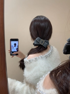 Détail d'un nœud papillon en laine gris foncé avec boucle strass sur cheveux longs