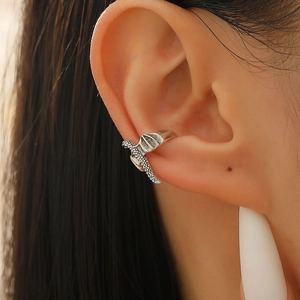 Detailed macro view of silver dragon ear cuff showing intricate scales and wing design