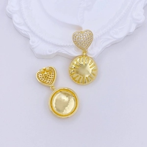 Detail of gold heart earrings with micro-inlaid zircons and radial textured round charms