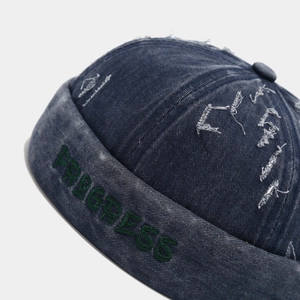 Dettaglio del cappello denim vintage con ricamo verde PROGRESS in rilievo laterale