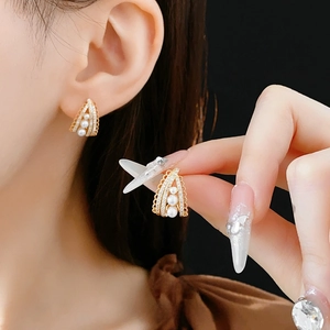 Elegant gold pearl stud earrings with zircon lace hollow design worn by a female model