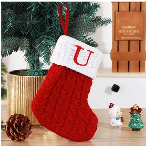 Gros plan d'une chaussette de Noël tricotée avec la lettre U rouge sur un sapin décoré