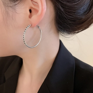 Gros plan d'une boucle d'oreille créole argentée en strass portée par un mannequin