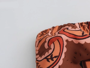 Gros plan détaillé du tissu élastique smocké avec motif ethnique paisley brun